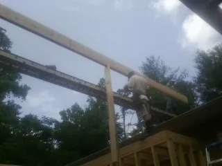 Carpenter setting a ridge beam over a new addition frame — Ice Dam Removal by Roofing Brothers in Scottsville