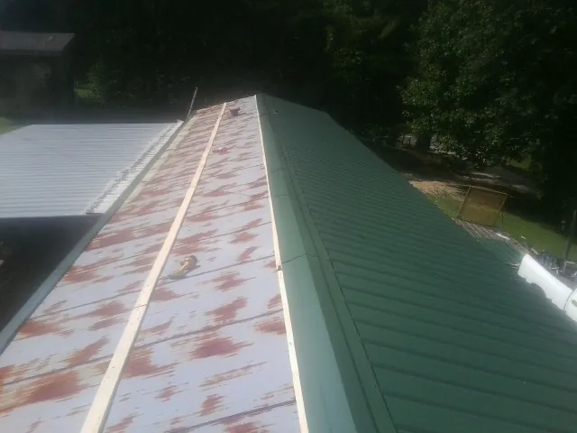 Old rusted panels beside newly installed green metal roofing — Wind Damage Roof Repair by Roofing Brothers in Scottsville