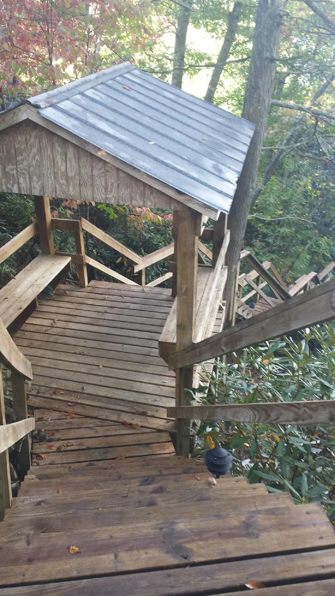 Metal roofed shelter over wooden steps on a wooded walkway — Skylight Repair & Installation work by our crew in Scottsville