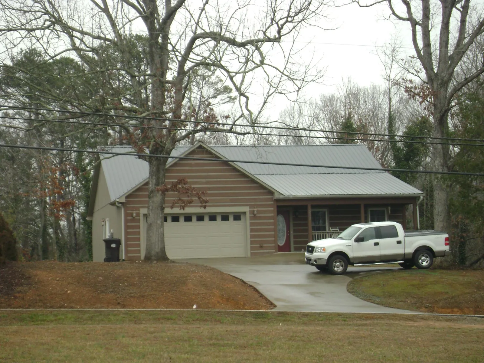 Gray metal roof on a log sided house with an attached two car garage in Scottsville